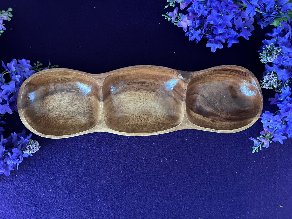 Wooden three-compartment bowl on a dark blue background with purple flowers