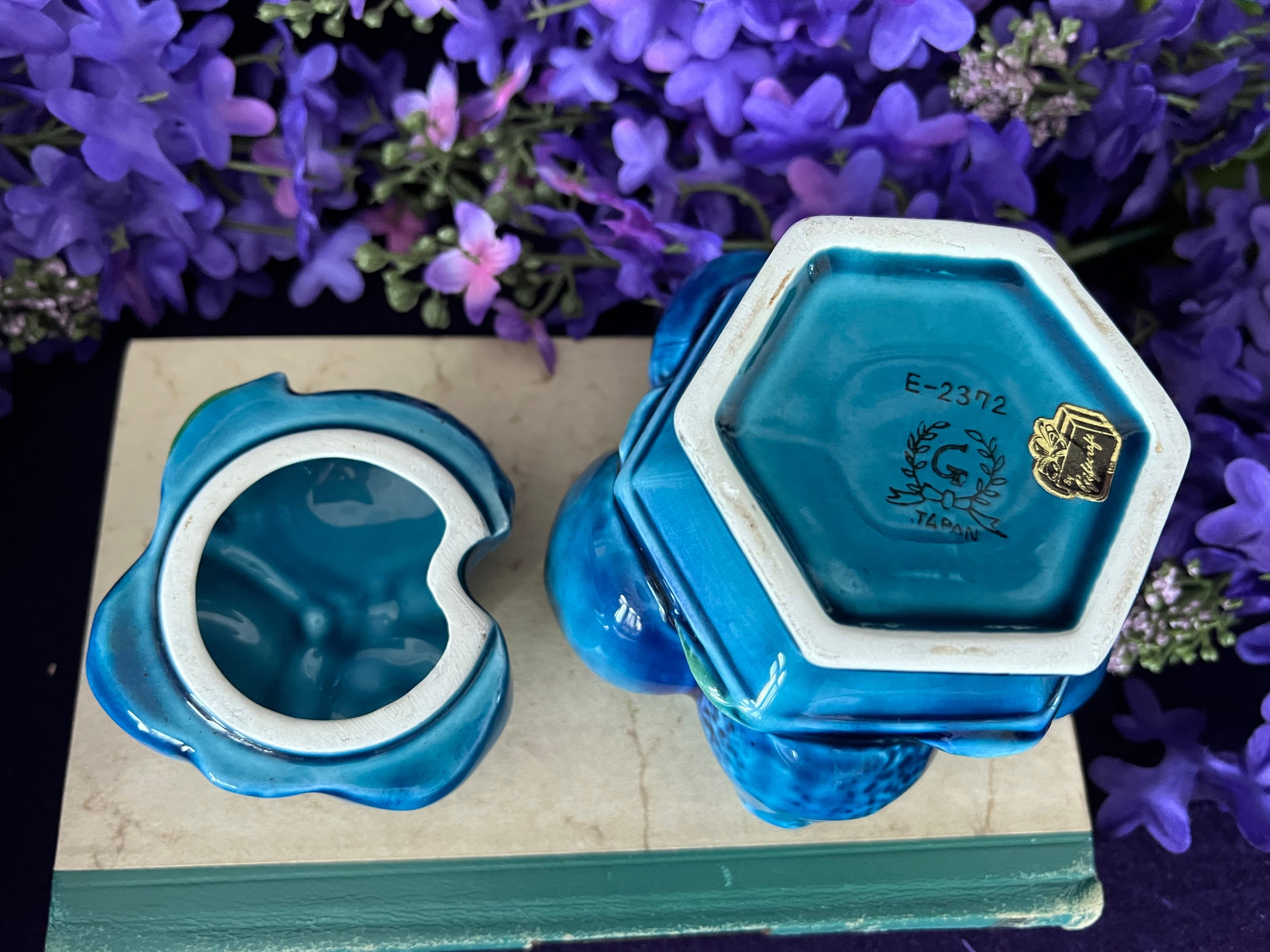 Blue ceramic item with white interior on a wooden surface with purple flowers in the background