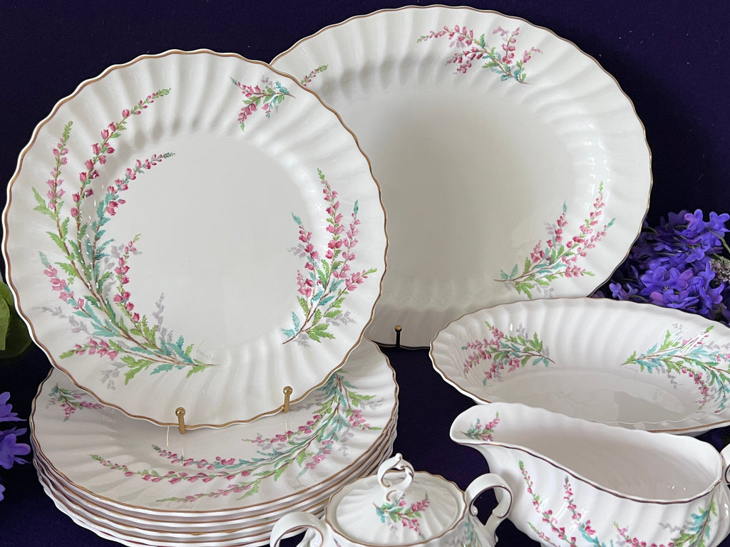 Set of ceramic plates and teacups with floral patterns on a dark background.